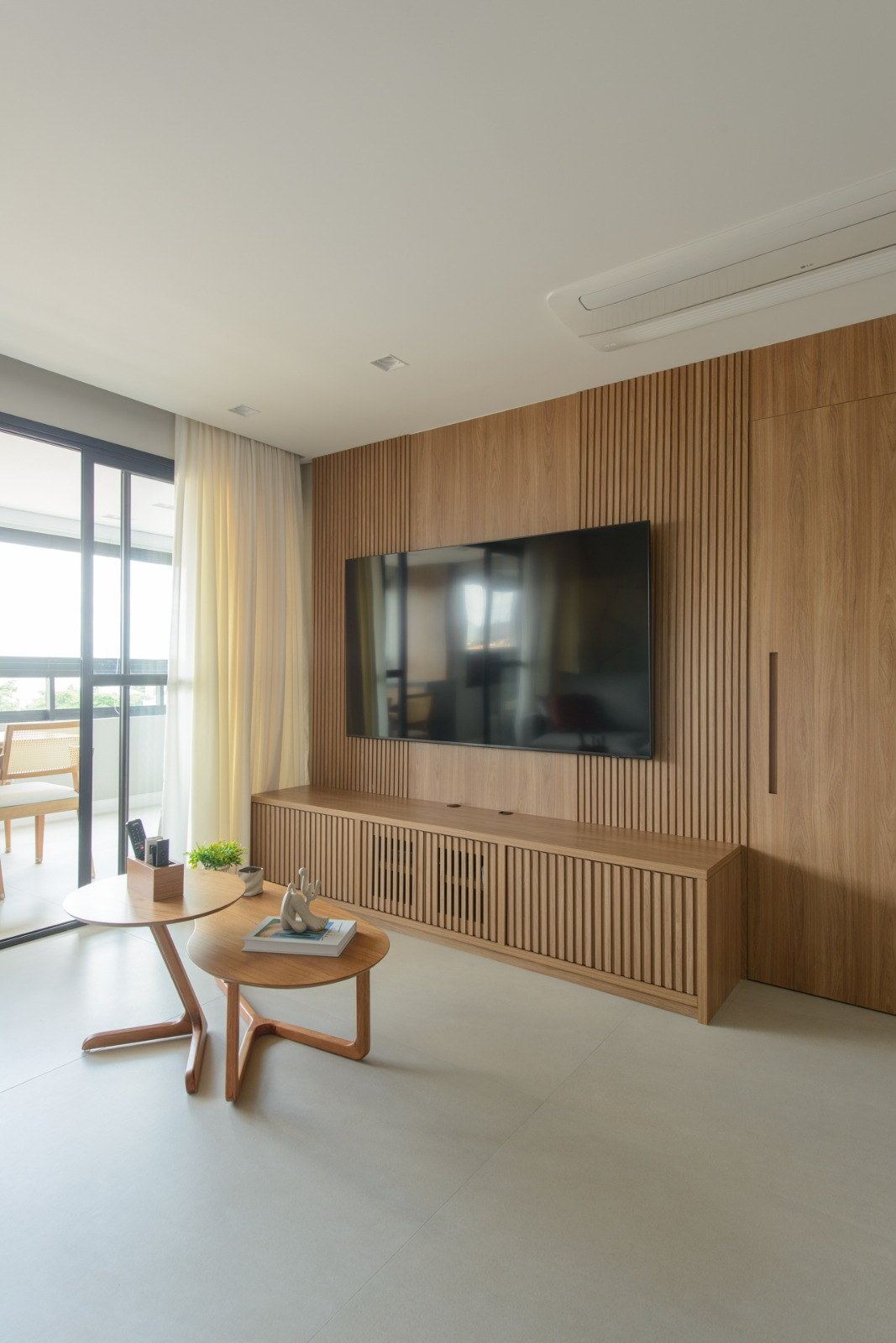 Parede da sala revestida em madeira, com ponto de TV embutido